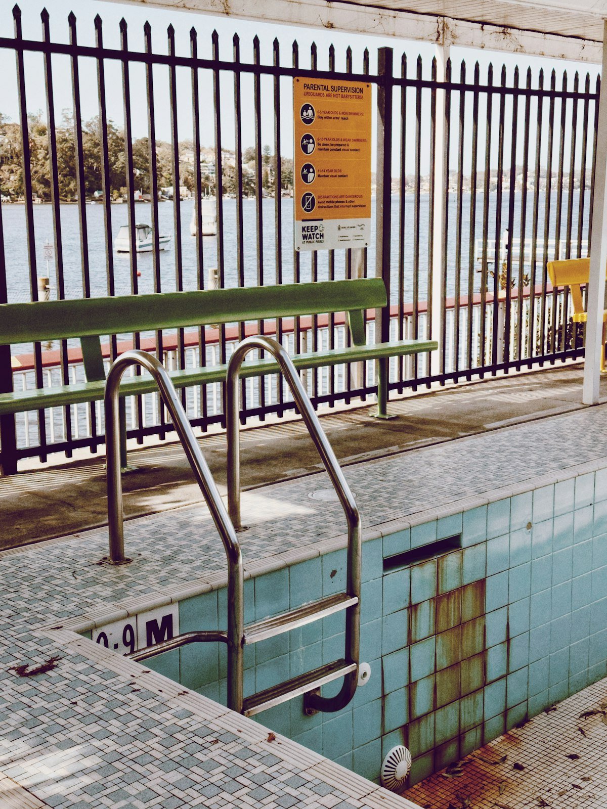 Ornamental steel pool fence with a posted parental supervision safety sign at a swimming pool