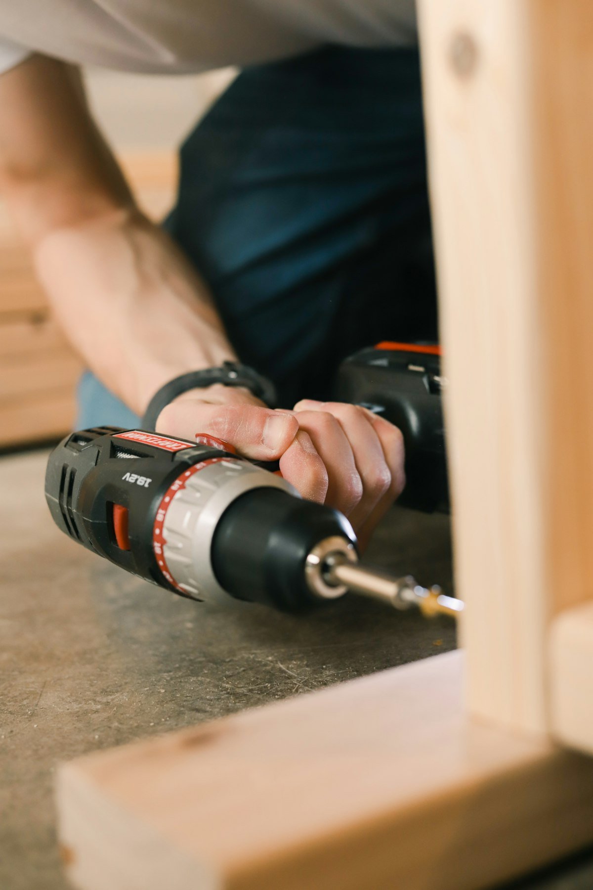 Person holding a cordless drill, a common tool for DIY wood fence installation
